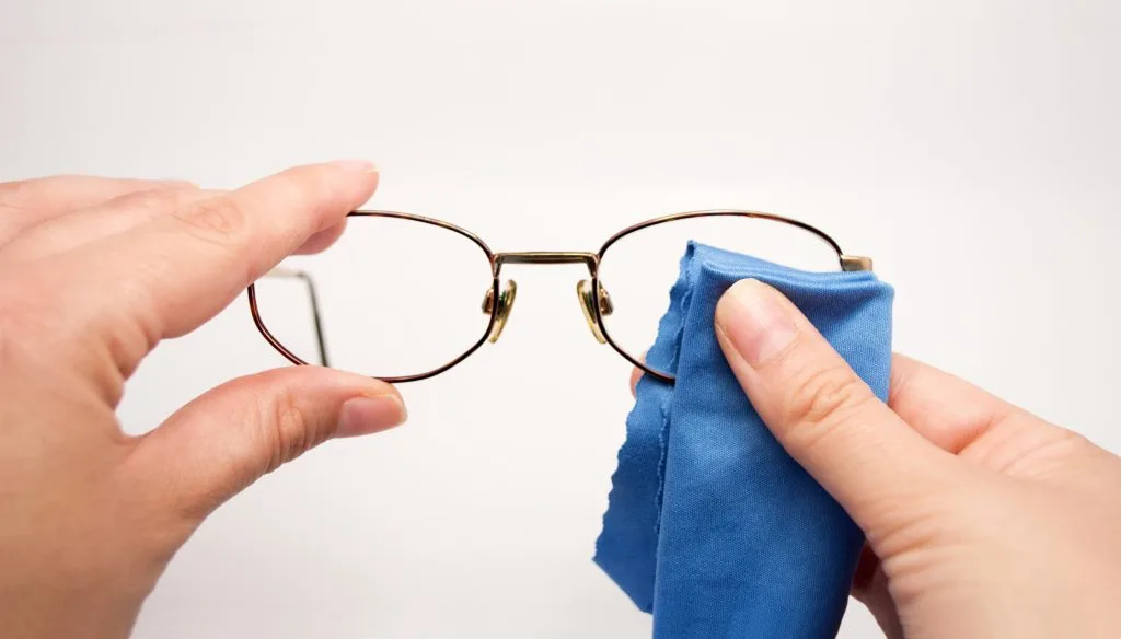 woman cleaning her glasses with microfiber cloth